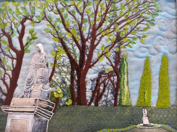 This Garden of Schoenbrunn Palace in Vienna in black and white on linen beckoned me to bring it to life. I started by embroidering the tree trunks and branches, and added leaves in confetti style. These were secured by machine stitching. The hedge was machine embroidered. Flowers were hand embroidered at the base of the hedge and around the small statue.